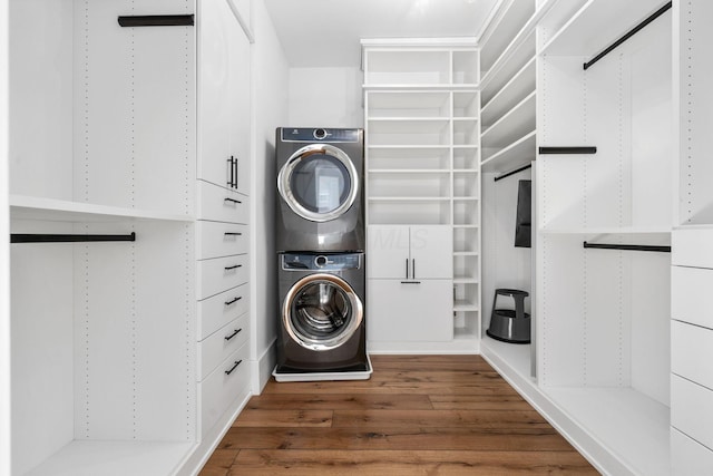 laundry area featuring stacked washer / dryer and dark hardwood / wood-style flooring