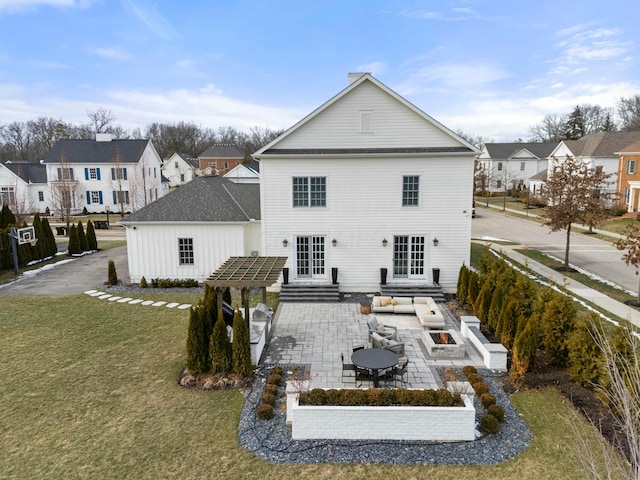 rear view of property featuring a patio, a yard, and an outdoor fire pit