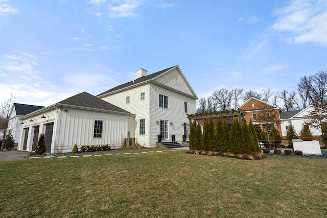 rear view of house featuring a garage, a yard, and a pergola