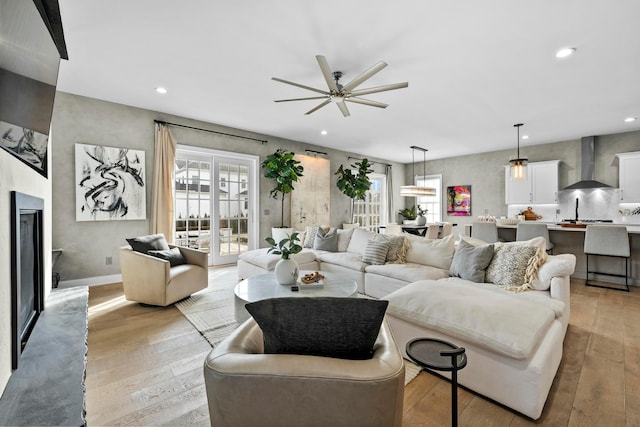 living room featuring ceiling fan, plenty of natural light, and light hardwood / wood-style flooring