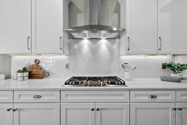 kitchen featuring ventilation hood, white cabinetry, stainless steel gas stovetop, and decorative backsplash