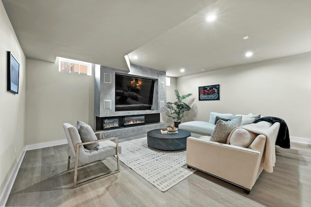 living room with a high end fireplace and light wood-type flooring