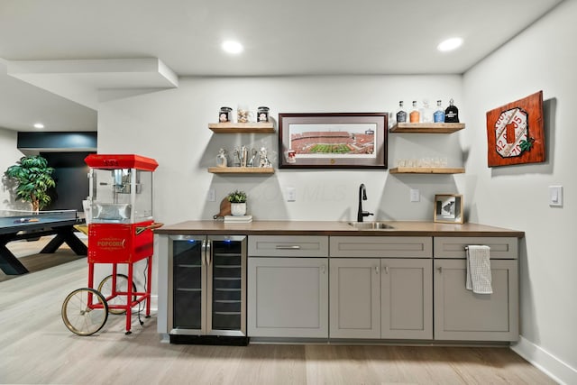 bar with gray cabinets, sink, wine cooler, and light hardwood / wood-style floors