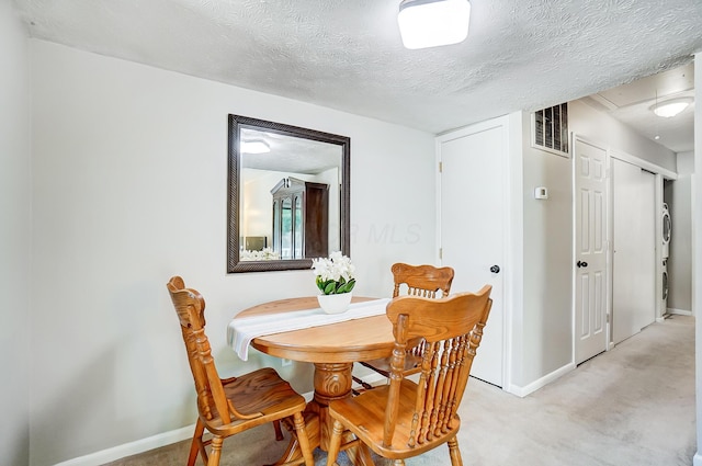 carpeted dining room featuring stacked washer and dryer and a textured ceiling