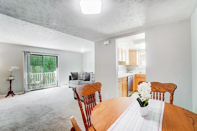 dining room featuring sink, carpet, and a textured ceiling