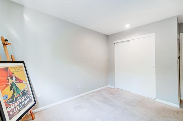 unfurnished bedroom featuring light colored carpet and a closet