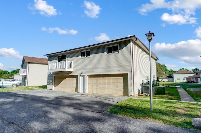 view of front of property featuring central AC unit, a garage, a front yard, and a balcony