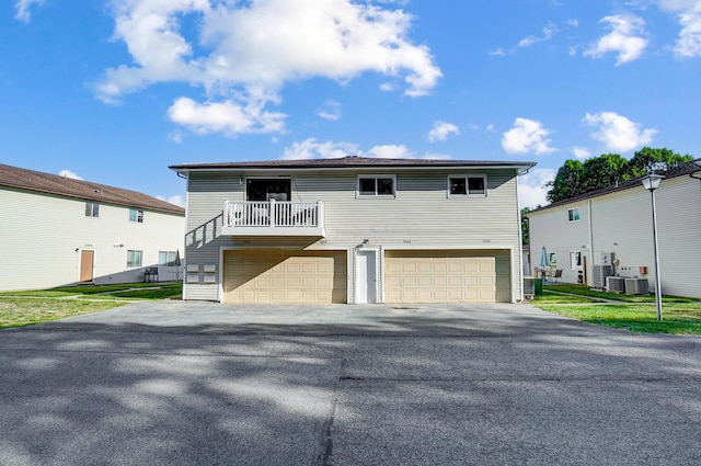 view of front of property featuring central AC unit, a garage, a front yard, and a balcony