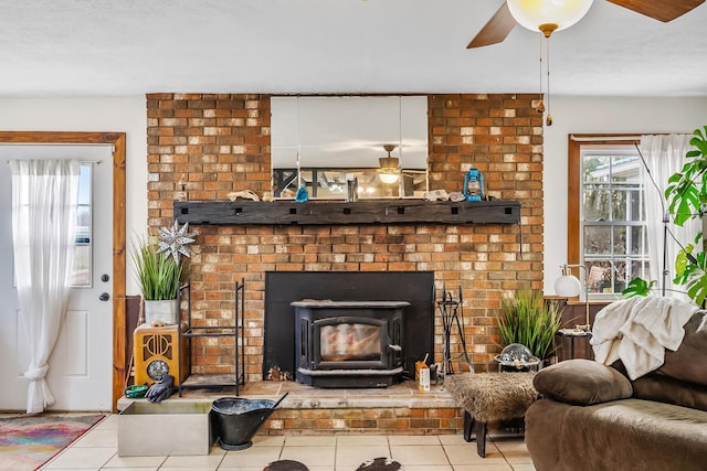 living room featuring light tile patterned flooring, ceiling fan, and a wood stove