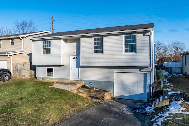 raised ranch featuring a garage and a front lawn