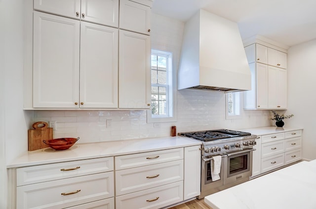 kitchen with white cabinetry, double oven range, custom range hood, and backsplash