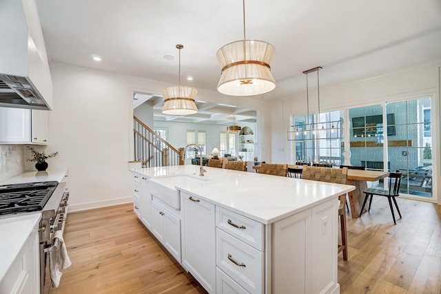 kitchen with a kitchen island with sink, extractor fan, pendant lighting, and a breakfast bar