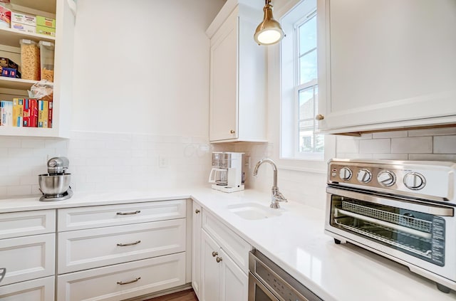 kitchen featuring tasteful backsplash, sink, and white cabinets