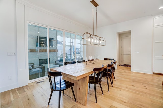 dining space featuring crown molding, an inviting chandelier, and light hardwood / wood-style flooring