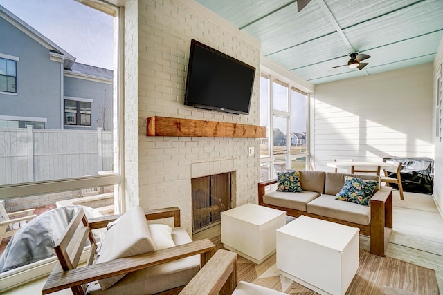 sunroom / solarium with a brick fireplace and ceiling fan