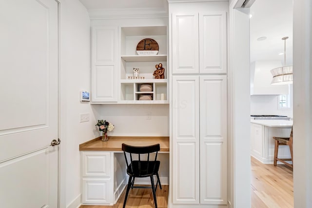 home office with built in desk and light hardwood / wood-style floors