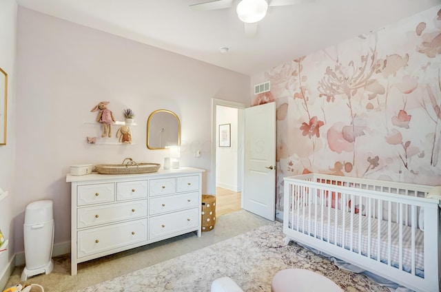 carpeted bedroom with a nursery area and ceiling fan