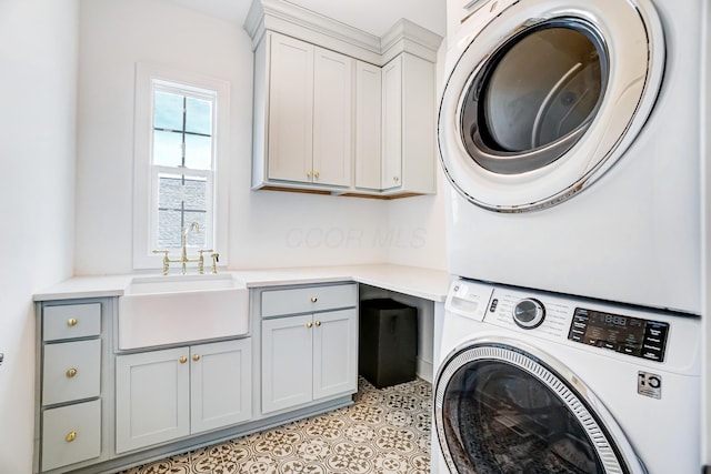 laundry room with cabinets, stacked washer and clothes dryer, and sink