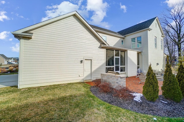 back of house with a sunroom, a lawn, and a patio area