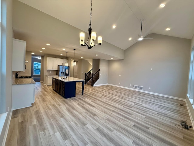 kitchen with pendant lighting, sink, white cabinetry, a center island, and light hardwood / wood-style floors