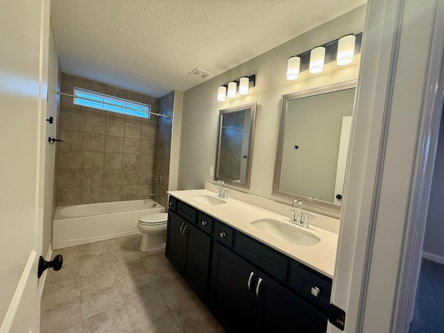 full bathroom featuring vanity, toilet, tiled shower / bath combo, and a textured ceiling