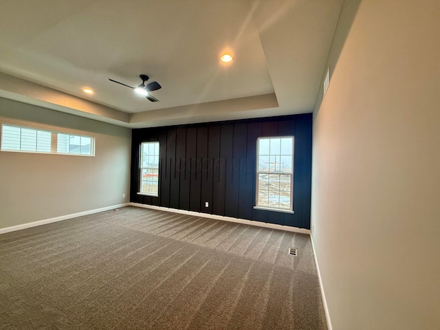 carpeted spare room with ceiling fan and a tray ceiling