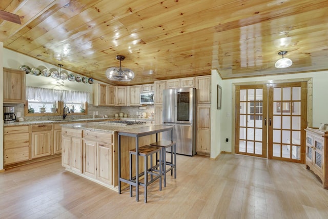 kitchen featuring french doors, hanging light fixtures, light brown cabinets, appliances with stainless steel finishes, and a kitchen island