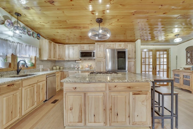 kitchen featuring sink, hanging light fixtures, light brown cabinets, appliances with stainless steel finishes, and a kitchen island