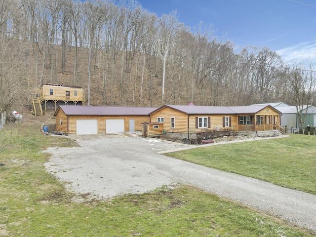 view of front of property featuring a garage, covered porch, and a front lawn