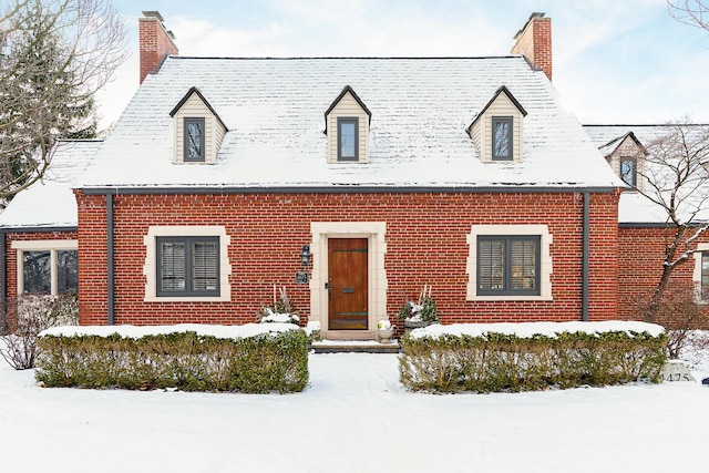 cape cod house with a chimney and brick siding