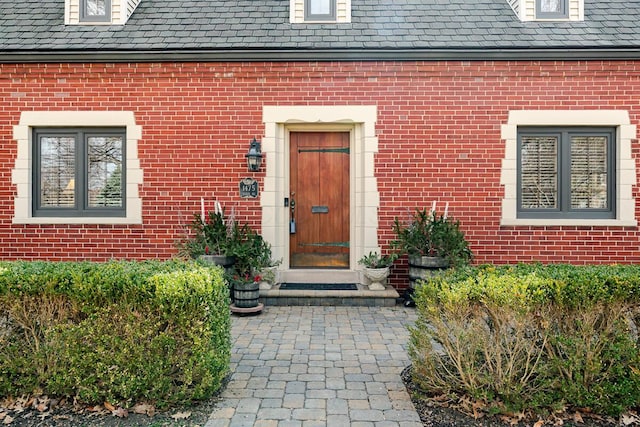 property entrance with a high end roof and brick siding