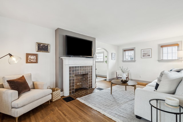 living room featuring a tiled fireplace and hardwood / wood-style flooring