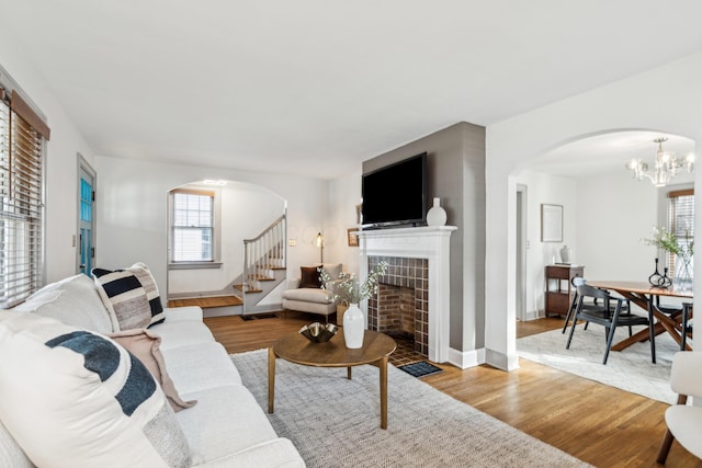 living room featuring a tile fireplace, a chandelier, and light wood-type flooring