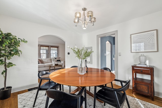 dining space featuring wood-type flooring and an inviting chandelier