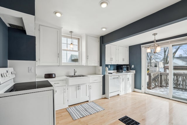 kitchen featuring sink, white cabinetry, pendant lighting, white appliances, and light hardwood / wood-style floors