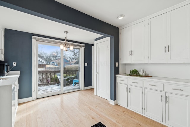 kitchen featuring a notable chandelier, decorative light fixtures, light hardwood / wood-style floors, and white cabinets