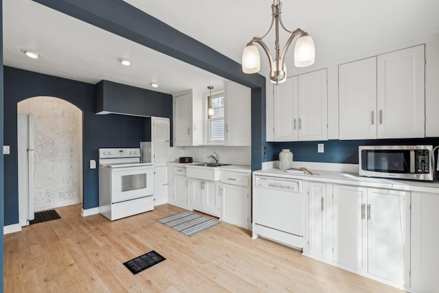 kitchen with hanging light fixtures, light wood-type flooring, white cabinets, and white appliances