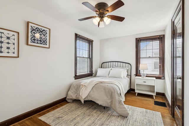 bedroom with ceiling fan, dark hardwood / wood-style flooring, and multiple windows