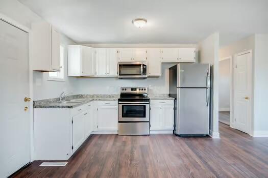 kitchen with white cabinetry, stainless steel appliances, dark hardwood / wood-style floors, and sink