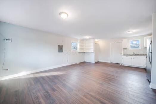 unfurnished living room featuring a wealth of natural light, electric panel, and dark hardwood / wood-style floors