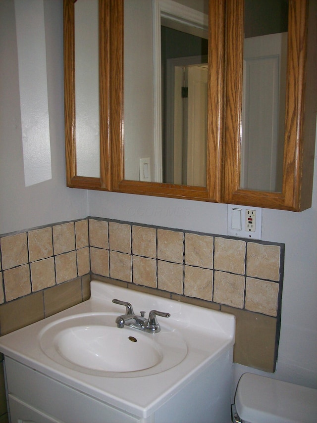 bathroom featuring toilet, sink, and backsplash