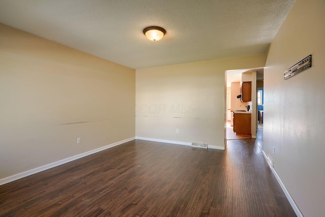 spare room with dark wood-type flooring and a textured ceiling