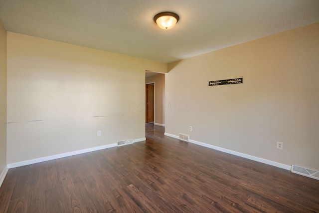 unfurnished room featuring a textured ceiling and dark hardwood / wood-style flooring