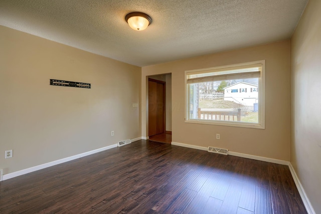 empty room with dark wood-type flooring and a textured ceiling