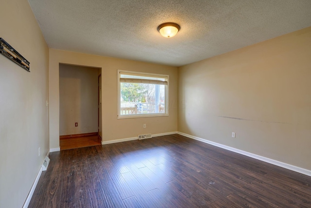 unfurnished room featuring dark wood-type flooring and a textured ceiling