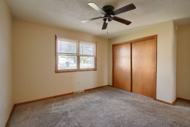 unfurnished bedroom with ceiling fan, light colored carpet, a closet, and a textured ceiling