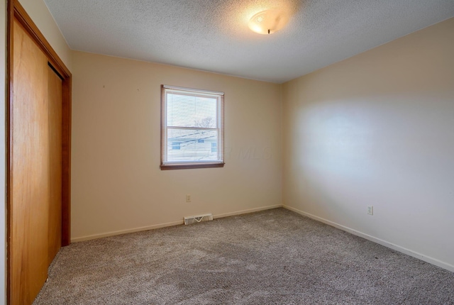 unfurnished bedroom featuring a closet, a textured ceiling, and carpet