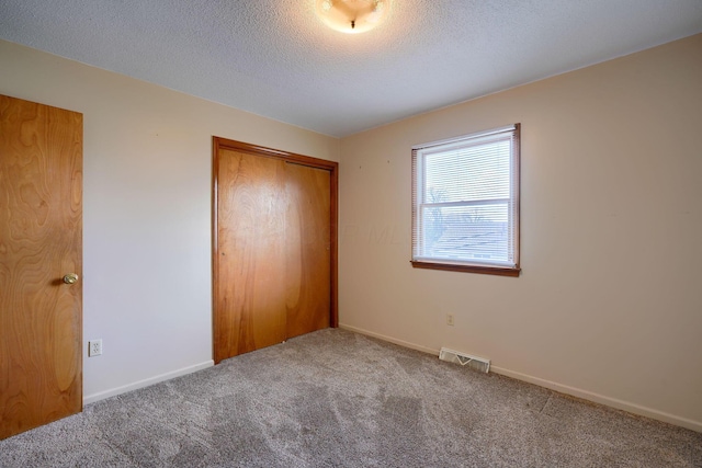 unfurnished bedroom with a closet, carpet, and a textured ceiling