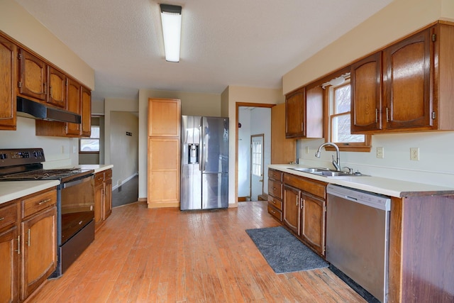 kitchen featuring sink, light hardwood / wood-style flooring, stainless steel appliances, and a textured ceiling