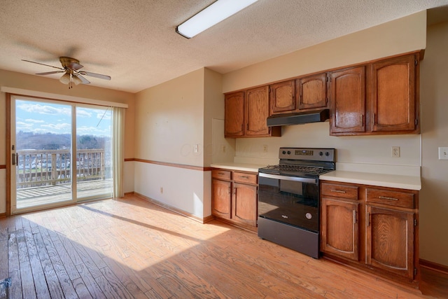 kitchen with ceiling fan, a textured ceiling, stainless steel electric range, and light hardwood / wood-style flooring